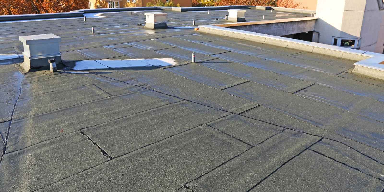professional roofer fixing drainage issues on flat roof